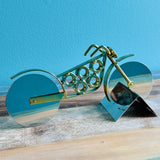 Gold motorcycle pizza cutter with stainless steel wheel blades on a teal stand